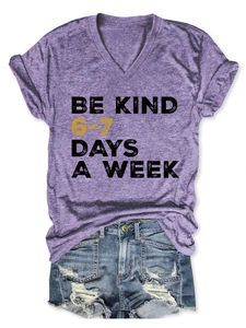 Flat lay of purple V-neck T-shirt with 'Be Kind' print and distressed denim shorts
