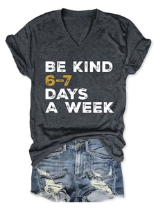 Flat lay of gray V-neck tee with Be Kind slogan and distressed denim shorts