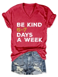 Detail of red V-neck Be Kind t-shirt paired with distressed denim shorts