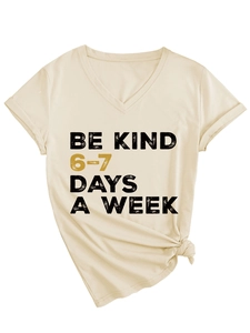 Detail of the V-neckline and BE KIND typography on this light beige cotton t-shirt
