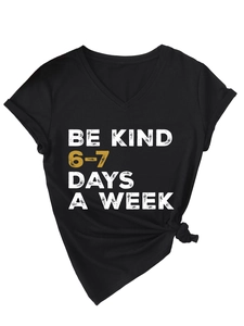 Close-up of Be Kind V-neck T-shirt with gold graphic slogan and side knot detail