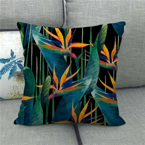 Detail of tropical bird of paradise floral print on linen pillowcase over a grey sofa