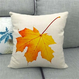 Close-up of autumn maple leaf print on a beige linen throw pillow cover on a sofa