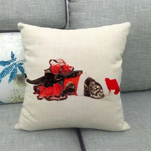 Close-up of linen pillowcase with cute cat in Christmas outfit on grey sofa