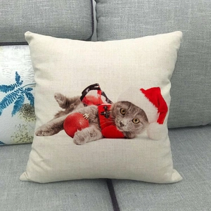Close-up of linen pillow cover featuring a festive cat with a red Santa hat on a grey sofa