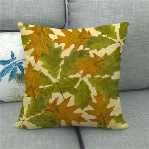 Detail shot of linen pillowcase with maple leaf prints on a soft grey fabric sofa