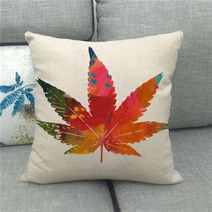 Close-up of linen pillowcase with colorful maple leaf print on a grey sofa