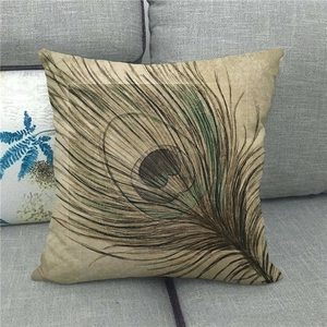 Nahaufnahme des Pfauenfedern-Aquarelldrucks auf Leinenkissenbezug auf grauem Sofa