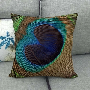 Linen peacock feather decorative pillow cover with eye pattern on a grey fabric sofa