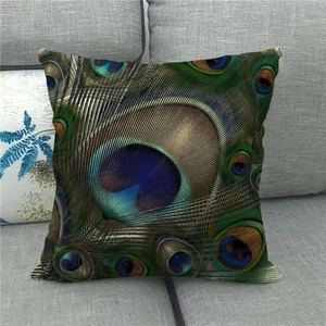 Detailed peacock feather pattern print on a square linen cushion cover displayed on a sofa