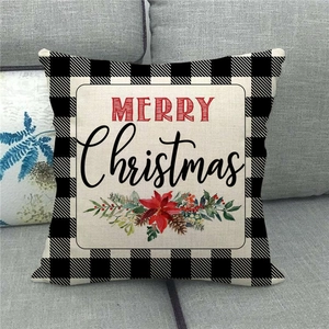 Close-up of Merry Christmas linen pillowcase with buffalo check border on a grey sofa