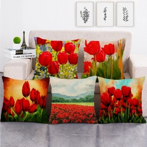 Five watercolor red tulip and poppy flower linen cushion covers on a sofa
