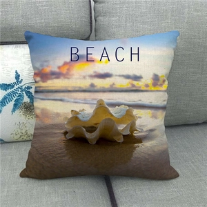 Détail de la housse de coussin en lin avec imprimé de coquillage et lettres BEACH bleues