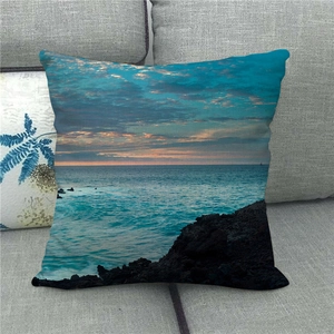 Détail d'une housse de coussin en lin montrant un paysage marin sur un canapé