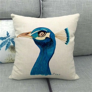 Detail of artistic peacock head illustration on a beige linen square pillowcase on sofa
