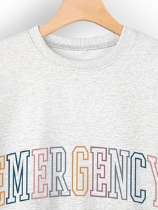 Detail of grey crewneck sweatshirt featuring ribbed collar and rainbow EMERGENCY print