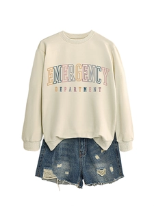 Flat lay of cream crewneck sweatshirt with emergency department print and ripped denim shorts