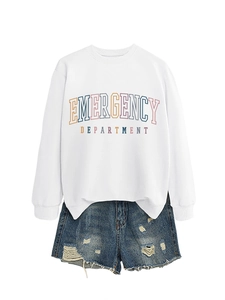 Close-up of Emergency Department print on white sweatshirt and ripped denim shorts