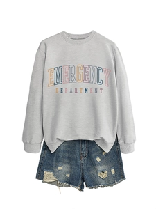 Detail of grey sweatshirt with emergency department art text and ripped denim shorts