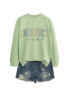Detail of light green sweatshirt with text print and distressed denim shorts