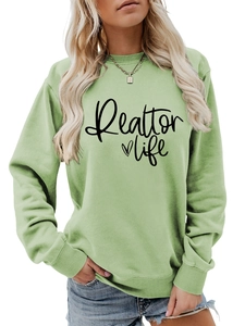 Detail of the light green sweatshirt featuring Realtor Life text and a small black heart
