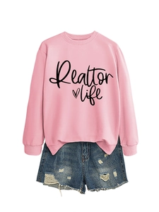 Flat lay of pink Realtor Life sweatshirt paired with distressed blue denim shorts