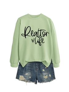 Detail of Realtor Life print on light green sweatshirt with distressed denim shorts