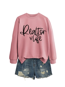 Detail of pink Realtor Life sweatshirt paired with distressed blue denim shorts