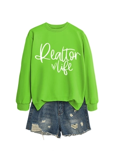 Detail of bright green Realtor Life sweatshirt with distressed blue denim shorts