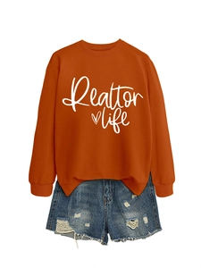 Flat lay of orange Realtor Life sweatshirt paired with distressed blue denim shorts