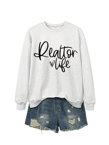 Detail of grey Realtor Life sweatshirt and distressed denim shorts with frayed edges