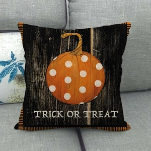 Detail of Trick or Treat pumpkin pillow cover on a grey sofa with orange dot pattern