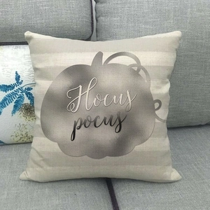 Close-up of beige linen pillow cover with silver Hocus Pocus pumpkin print on a sofa