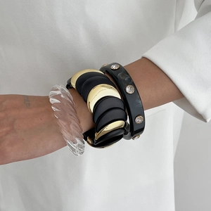 Tre bracciali grossi in resina con trama marmorea e accenti dorati sul braccio di una modella