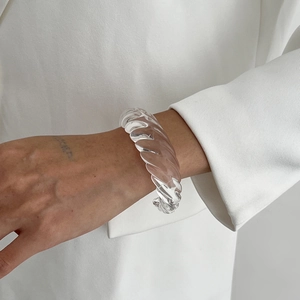 Macro di un elegante bracciale a spirale in resina trasparente su blazer bianco