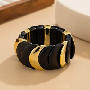 Dettaglio di un ampio bracciale elastico con scaglie nere testurizzate e oro lucido