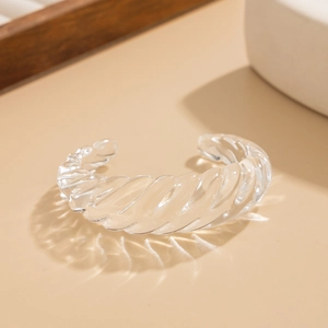 Dettaglio di un bracciale rigido aperto in acrilico trasparente con texture effetto ghiaccio
