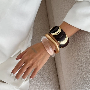 Set of chunky geometric acrylic and matte gold bracelets on a model wrist