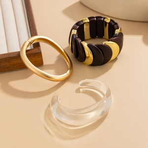 Detailed close-up of mixed material geometric elastic bracelets in gold and resin