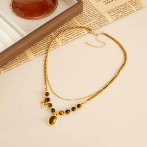 Detail view of double-layer necklace with tiger eye beads and gold cross pendant