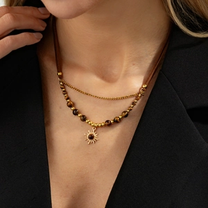 Detail of double-layer necklace with sun pendant and tiger eye stone beads on a model