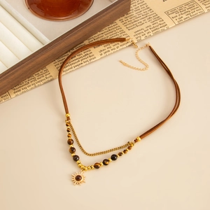 Detail of layered necklace featuring brown leather cord, tiger eye beads and sun pendant