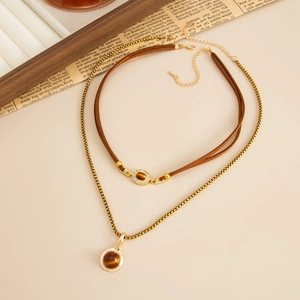 Detail of vintage layered tiger eye stone pendants with golden snake chain and leather cord