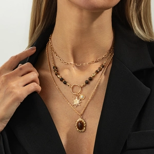 Detail of layered gold necklaces with tiger eye stone pendants on a black blazer