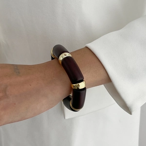 Detailed close-up of dark brown and gold segmented stretch bracelet on model wrist
