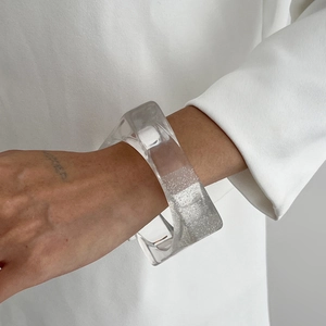 Gros plan du bracelet en résine transparente avec paillettes argentées sur fond blanc