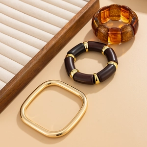 Detailed set of amber resin cuff, dark brown beaded bracelet, and gold geometric bangle