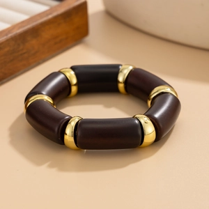 Detailed view of elastic bracelet with dark brown cylindrical beads and gold metal spacers