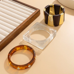 Ensemble de trois bijoux avec bracelet en métal doré et bracelets en résine sur présentoir