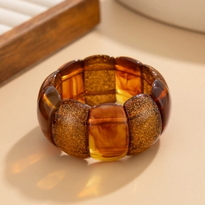 Macro detail of amber resin stretch bracelet with sparkling gold glitter inclusions